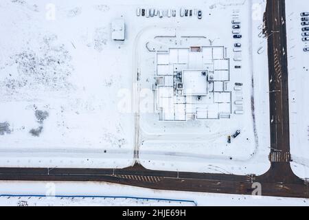 Schneebedecktes Dach eines Hochhauses, neu gebaut in Wohnviertel. Winter Luftaufnahme von oben. Stockfoto