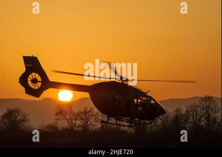 Serbische Luftwaffe Airbus Helicopters H145M zweimotoriger Hubschrauber, der abfliegt, Silhouette bei Sonnenuntergang Stockfoto