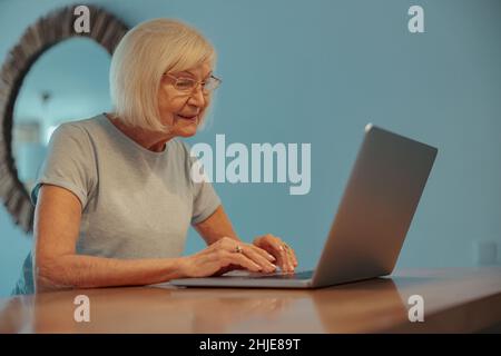 Eine Frau im modernen Alter, die zu Hause einen Laptop verwendet Stockfoto