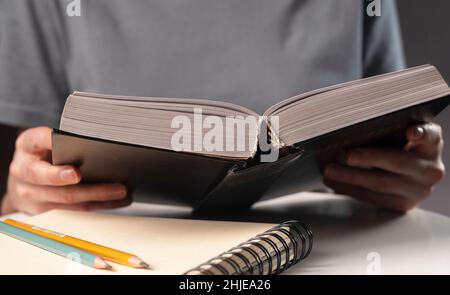 Studentinnen zeigen in der Nähe auf Text in Büchern oder Lehrbüchern, suchen nach Informationen und lesen nachts. Stockfoto