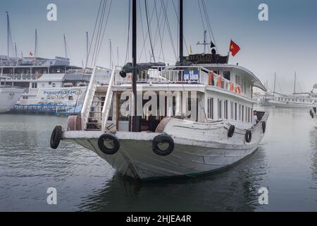 Halong Bay, Vietnam - 12. Dez 2015: Weiße Touristenboote vertäuten in der Halong Bay in der morgendlichen Wintersonne. Stockfoto