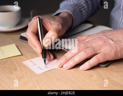 Geschäftsmann händiges Schreiben von Memonotizen oder Erinnerung auf Sticker am Schreibtisch. Stockfoto