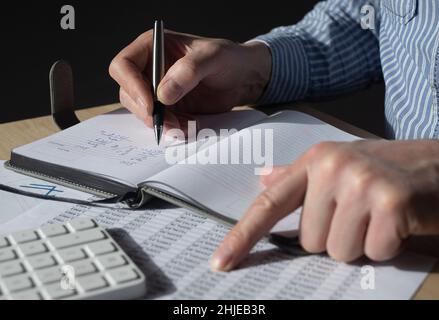 Geschäftsmann, der mit Finanzdokumenten, Rechnungslegungsstatistiken arbeitet. Steuerberechnungen und Budgetkonzept. Stockfoto