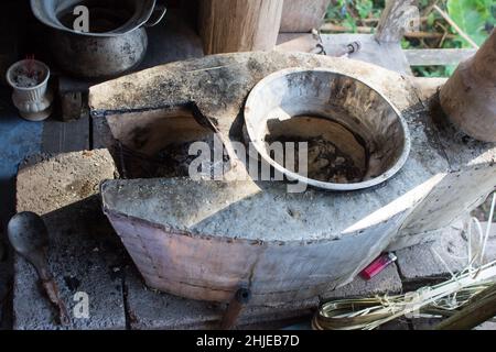 Traditionelle Art und Weise der Herstellung von Lebensmitteln auf offenem Feuer in einer alten Küche in einem Dorf Hotel, Kerala Indien. Töpfe und Pfannen auf dem Herd über einem natürlichen Feuer zum Kochen Stockfoto