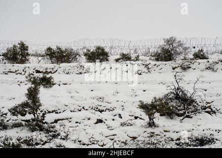 Ein Stacheldrahtzaun, der an einem verschneiten Tag zwischen israelischen und palästinensischen Gebieten in den Judäa-Bergen in der Nähe von Jerusalem trennt. Stockfoto