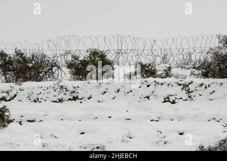 Ein Stacheldrahtzaun, der an einem verschneiten Tag zwischen israelischen und palästinensischen Gebieten in den Judäa-Bergen in der Nähe von Jerusalem trennt. Stockfoto