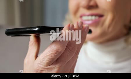 Frau mittleren Alters spricht über ein Smartphone über Lautsprecher Stockfoto