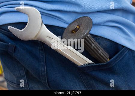 Schraubenschlüssel in der Gesäßtasche der Jeans. Große und kleine Schraubenschlüssel als Symbol für Vater und Sohn. Vatertag Hintergrund mit Papa- Schraubenschlüssel und Sohn - Schraubenschlüssel. Hap Stockfoto