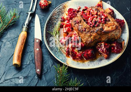 Schweinelende in einer fruchtigen Marinade. Gebratenes Fleisch mit Granatapfel. Weihnachtliches Essen Stockfoto