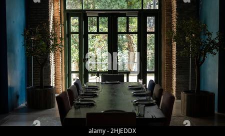 Luxuriöse Wohnzimmereinrichtung in einem alten Schloss. Fenster mit einer Tür zum Garten. Holztisch serviert. Alte Backsteinmauern Stockfoto