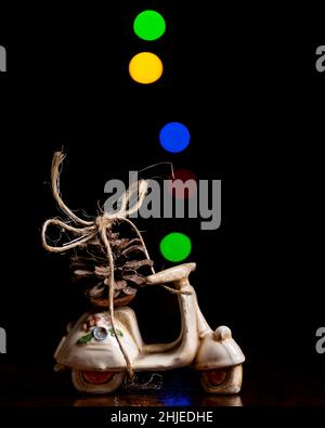 Ein Pinienkegel mit Schnur an einem Modell Roller mit farbigen Lichtern mit Bokeh-Effekt im Hintergrund gebunden Stockfoto