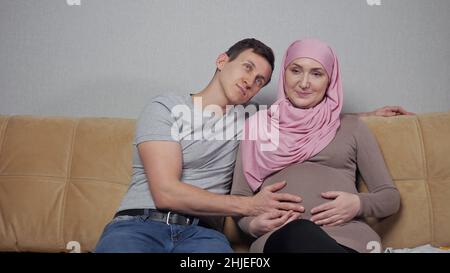 Muslimische Mutter und Vater streicheln schwanger Bauch lächelnd Stockfoto