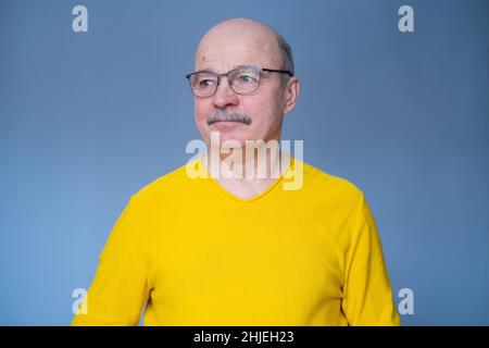 Älterer hispanischer Mann, der seine neue Brille probiert. Studio auf blauem Hintergrund aufgenommen Stockfoto