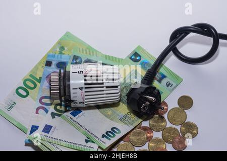 Die Energiepreise steigen und der Energieverbrauch Thermostat-Regler Heizung und Strom Stecker mit viel Geld Stockfoto