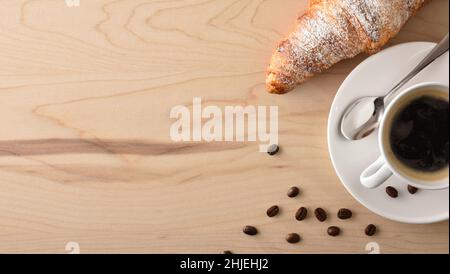 Weiße Porzellanbecher mit heißem Kaffee und Croissant auf braunem Holztisch zum Frühstück. Draufsicht. Horizontale Panoramakomposition. Stockfoto