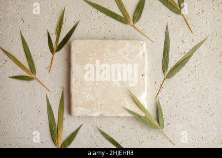 Travertin Stein Display flach Lay Podium auf biege Hintergrund und Bambusblätter. Produktförderung Beauty Kosmetik Schaufenster. Stockfoto
