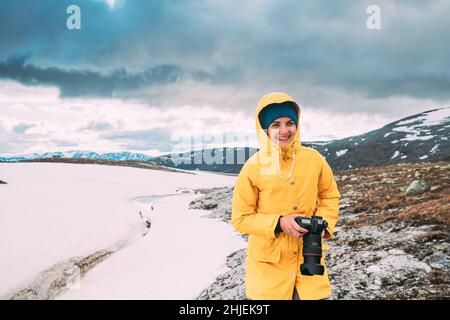 Aurlandsfjellet, Norwegen. Glückliche junge Frau touristische Reisende Fotograf mit der Kamera zu Fuß in der Nähe von Aurlandsfjellet Scenic Route Straße. Aktiven Lebensstil Stockfoto