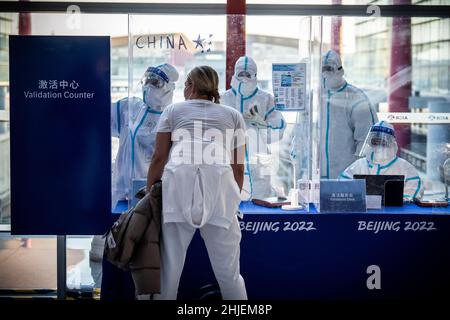 Peking, China. 29th Januar 2022. Helfer in voller Schutzausrüstung sprechen am Flughafen Peking mit einem Athleten aus der Ukraine. Athleten, Delegationen und Journalisten, die zu den Olympischen Winterspielen 2022 mit speziellen Charterflugzeugen anreisen, werden mit speziellen Sicherheitsmaßnahmen behandelt. Quelle: Michael Kappeler/dpa/Alamy Live News Stockfoto