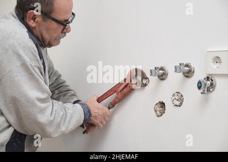 Leitender Klempner mit einer Schlupfgelenkzange, um den Anschluss an einem Rohr zu befestigen. Stockfoto