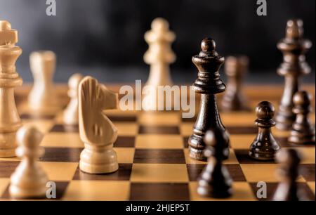 Schachspiel mit schwarzen und weißen Holzstücken auf einem Holzchessboard. Stockfoto