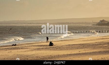 Portobello, Edinburgh, Schottland, Großbritannien. 29th. Januar 2022. Sturm Malik peitscht den Sand am Meer durch den Firth of Forth Temperatur von 9 Grad Celsius. Im Bild: Der Sand am Strand wirbelt in den starken, böigen Winden, die der Sturm Malik hervorgebracht hat. Im Bild: Hündin und ihr Hund sitzen am Strand, umgeben von wirbelndem Sand. Kredit: Newsandmore/alamy Live Nachrichten. Stockfoto