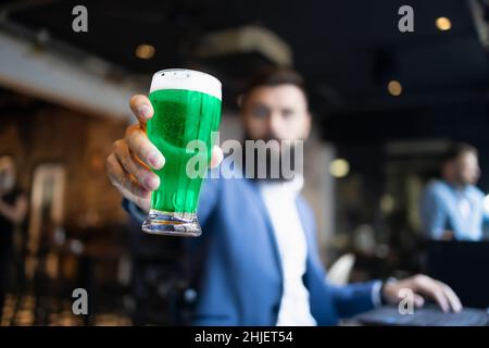 Ein Mann, der während des St. Patrick's Day in einem Pub ein grünes Glas Bier hält Stockfoto