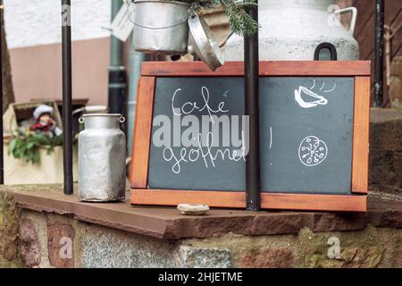 Tafel mit der handgeschriebenen Botschaft mit den deutschen Worten für Café öffnet sich vor einem kleinen Restaurant in einer deutschen Altstadt. Stockfoto