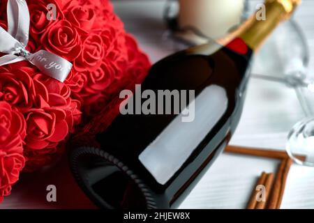 Flasche Champagner, Rosen, Zimtstangen und ein Glas auf weißem Hintergrund. Draufsicht Stockfoto