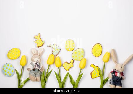 Hausgemachte Brötchenplätzchen aus Ostern mit Icing, verzierten Eiern und Tulpen auf weißem Hintergrund/Fröhliches osterkonzept. Kopierbereich, flaches Layout, Vorlage Stockfoto