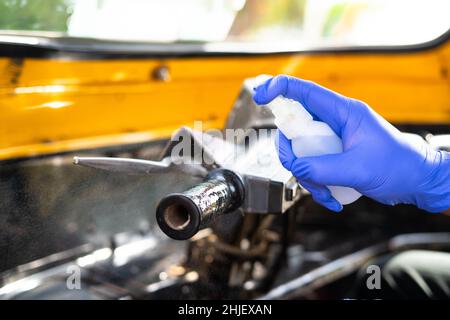 Nahaufnahme, Auto-Rikscha-Fahrer mit Schutzhandschuhen Sprühen Desinfektionsmittel vor Coronavirus covid Pandemie zu schützen - Konzept der Hygiene Stockfoto