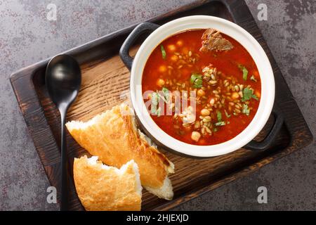 Chorba Frik ist eine traditionelle Suppe aus Lamm, geknackter Weizen, Tomaten, Zwiebeln, Sellerie, Koriander, Paprika, Petersilie in Nahaufnahme auf einem Teller auf dem Tisch Stockfoto