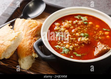 Chorba Frik ist eine traditionelle Suppe aus Lamm, geknackter Weizen, Tomaten, Zwiebeln, Sellerie, Koriander, Paprika, Petersilie in Nahaufnahme auf einem Teller auf dem Tisch Stockfoto