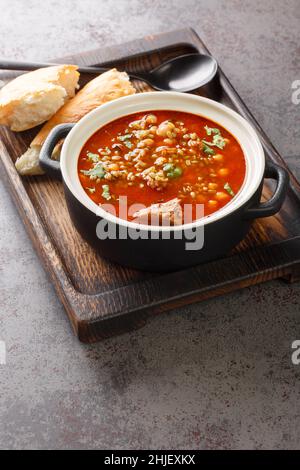 Chorba Hamra bel Frik algerisches Lamm, Tomate und Freekeh-Suppe in Nahaufnahme auf einem Teller auf dem Tisch. Vertikal Stockfoto