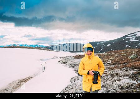 Aurlandsfjellet, Norwegen. Glückliche junge Frau touristische Reisende Fotograf mit der Kamera zu Fuß in der Nähe von Aurlandsfjellet Scenic Route Straße. Aktiven Lebensstil Stockfoto