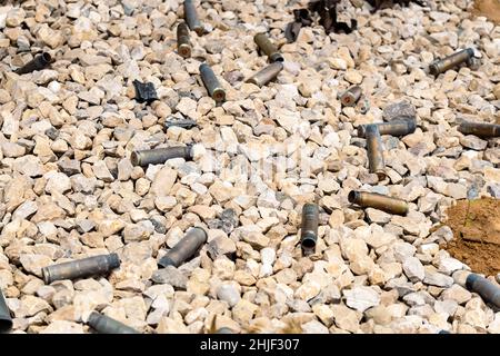 Leere Kugel- oder Patronengehäuse, die auf dem Boden verteilt sind. Auf dem Schießstand. Stockfoto