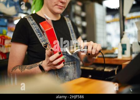 Crop weibliche Verkäuferin Scannen Barcode auf Box während der Arbeit an Kasse im Geschäft Verkauf von Fahrrad-Waren Stockfoto