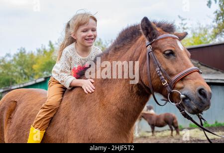 Glückliches kleines Mädchen Reiten Pony Pferd bareback und lachen Stockfoto