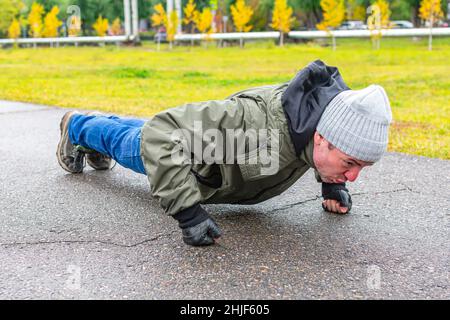 Mann tut Liegestütze im Park tun Übungen, um Brustmuskeln aufzubauen Stockfoto