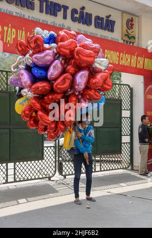 Ein Ballonverkäufer mit herzförmigen Ballons wartet am Valentinstag vor einer Schule in Hanoi, Vietnam, Südostasien Stockfoto