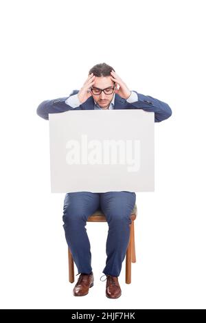 Fatigue Geschäftsmann sitzt auf einem Stuhl mit einem großen leeren Banner mit Platz für die Kopie von Nachrichten, hält Hände an Kopf Geste. Volle Länge überfordert busi Stockfoto