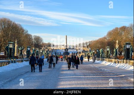 Besucher des Frognerparks und des Vigeland Skulpturenparks gehen über eine Brücke, die von Bronzeskulpturen von Gustav Vigeland, Oslo, Norwegen gesäumt ist. Stockfoto