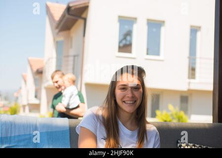 Die schöne Mutter lächelt und posiert, während der Vater sich um die Kinder kümmert Stockfoto