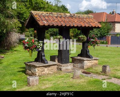 Die mit Blumen geschmückte Dorfpumpe auf dem Grün in Linton, West Yorkshire Stockfoto