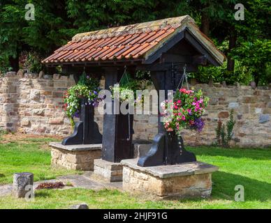 Die mit Blumen geschmückte Dorfpumpe auf dem Grün in Linton, West Yorkshire Stockfoto