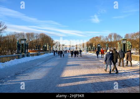 Besucher des Frognerparks und des Vigeland Skulpturenparks gehen über eine Brücke, die von Bronzeskulpturen von Gustav Vigeland, Oslo, Norwegen gesäumt ist. Stockfoto