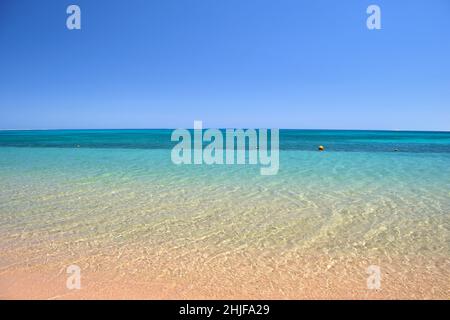 Seascape mit der Oberfläche des blauen Meerwassers mit kleinen Wellen, die auf den gelben Sandstrand krachen. Reise- und Urlaubskonzept. Stockfoto