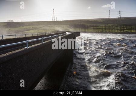 West Yorkshire, Großbritannien. 29th Januar 2022. Wetter in Großbritannien. BAITINGS Reservoir, Ripponden, West Yorkshire, Großbritannien. Sturm Maliks starker Wind peitscht das Wasser im Baitings Reservoir in der Nähe von Ripponden West Yorkshire und erzeugt große Wellen und einen Wassernebel durch die Staudämme. Der Nebel fängt das Sonnenlicht ein und erzeugt einen Regenbogen. Stockfoto