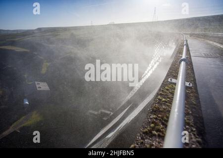 West Yorkshire, Großbritannien. 29th Januar 2022. Wetter in Großbritannien. BAITINGS Reservoir, Ripponden, West Yorkshire, Großbritannien. Sturm Maliks starker Wind peitscht das Wasser im Baitings Reservoir in der Nähe von Ripponden West Yorkshire und erzeugt große Wellen und einen Wassernebel durch die Staudämme. Der Nebel fängt das Sonnenlicht ein und erzeugt einen Regenbogen. Stockfoto