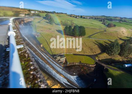 West Yorkshire, Großbritannien. 29th Januar 2022. Wetter in Großbritannien. BAITINGS Reservoir, Ripponden, West Yorkshire, Großbritannien. Sturm Maliks starker Wind peitscht das Wasser im Baitings Reservoir in der Nähe von Ripponden West Yorkshire und erzeugt große Wellen und einen Wassernebel durch die Staudämme. Der Nebel fängt das Sonnenlicht ein und erzeugt einen Regenbogen. Stockfoto
