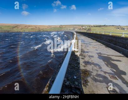 West Yorkshire, Großbritannien. 29th Januar 2022. Wetter in Großbritannien. BAITINGS Reservoir, Ripponden, West Yorkshire, Großbritannien. Sturm Maliks starker Wind peitscht das Wasser im Baitings Reservoir in der Nähe von Ripponden West Yorkshire und erzeugt große Wellen und einen Wassernebel durch die Staudämme. Der Nebel fängt das Sonnenlicht ein und erzeugt einen Regenbogen. Stockfoto